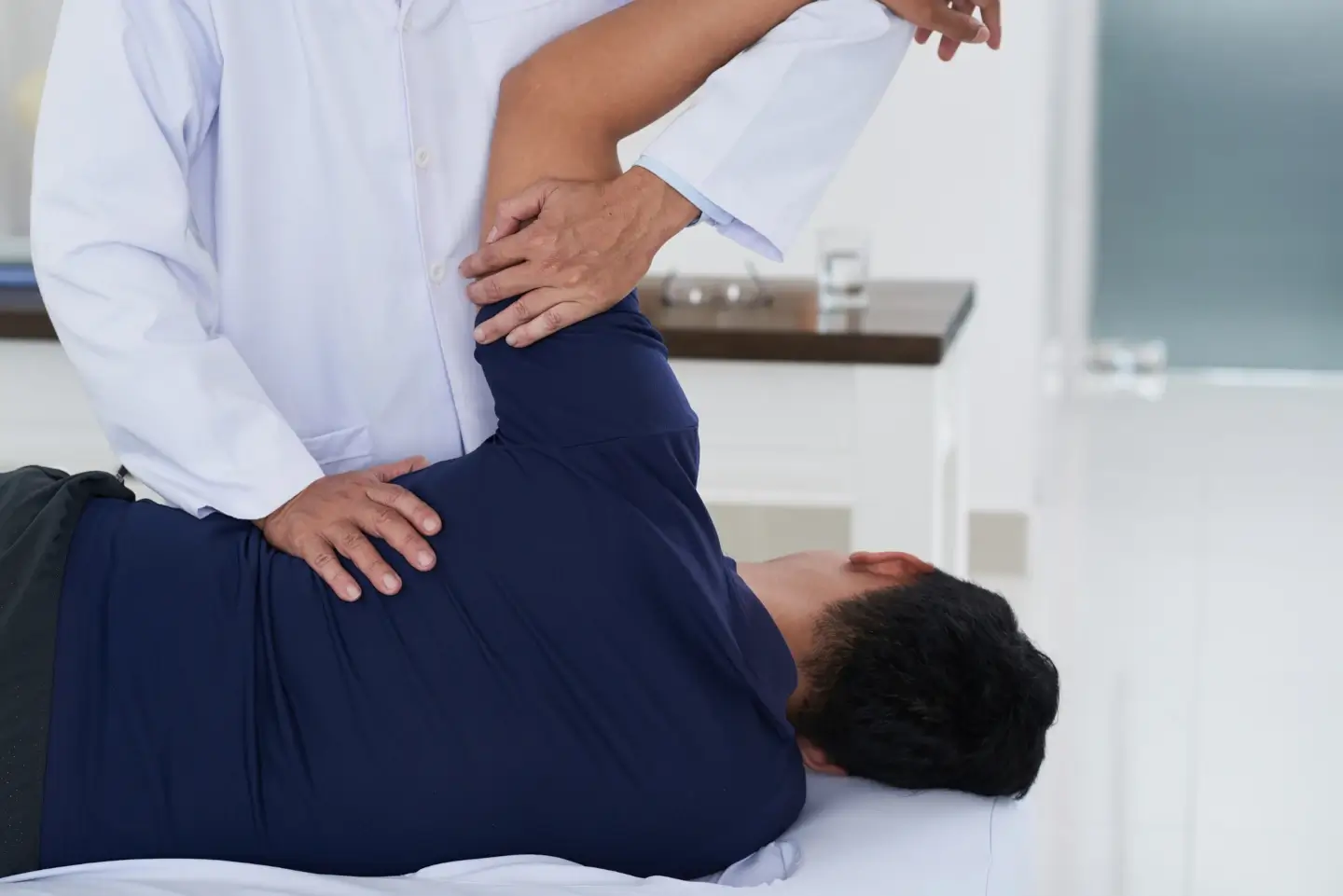 Chiropractor providing shoulder and upper back treatment during whiplash rehabilitation